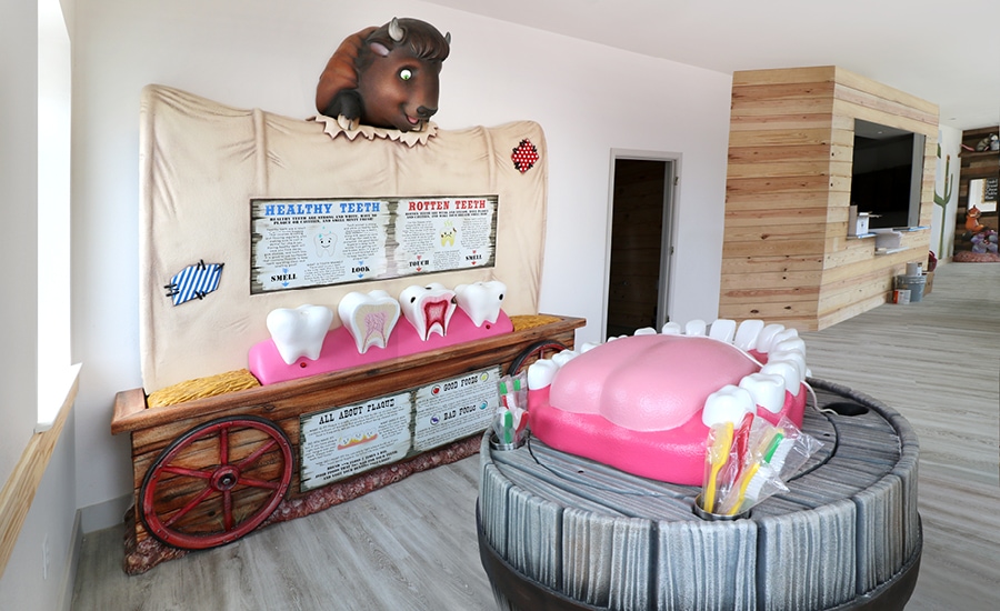Kid's dental education area with custom buffalo sculpture, wagon, and teeth sculptures in dental office.