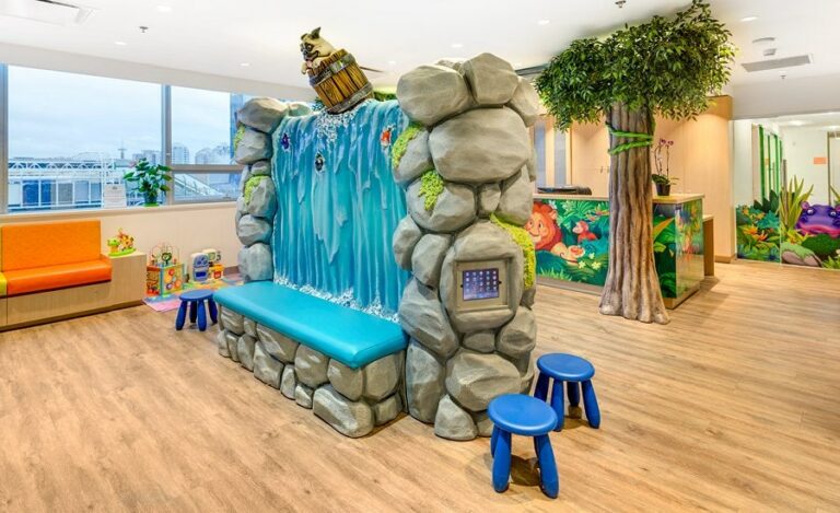 Custom, sculpted waterfall bench seat with a pug dog in a barrel going over the falls. A gaming pad is mounted on the rock face.