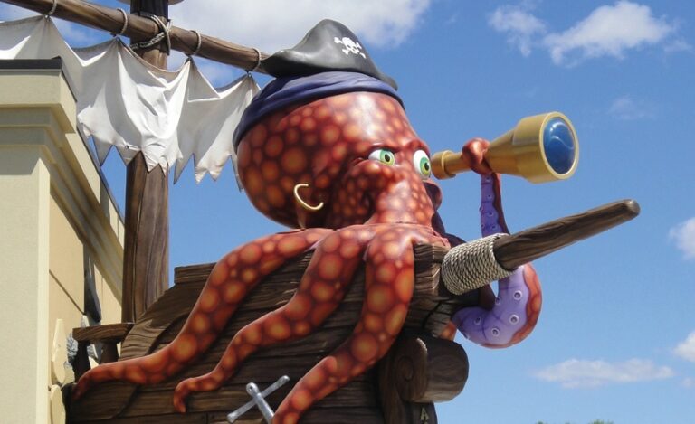 Giant, sculpted exterior pirate octopus character looking through a spy glass at the front of a pirate ship.