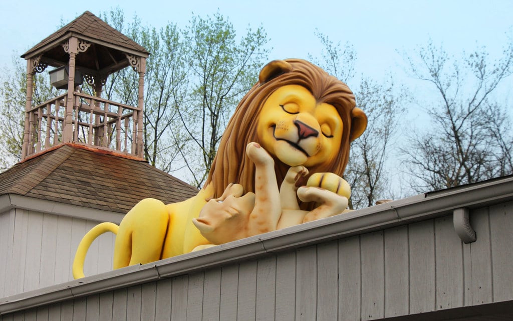Giant sculpted lion and cub landmark character on roof of pediatric dental office.