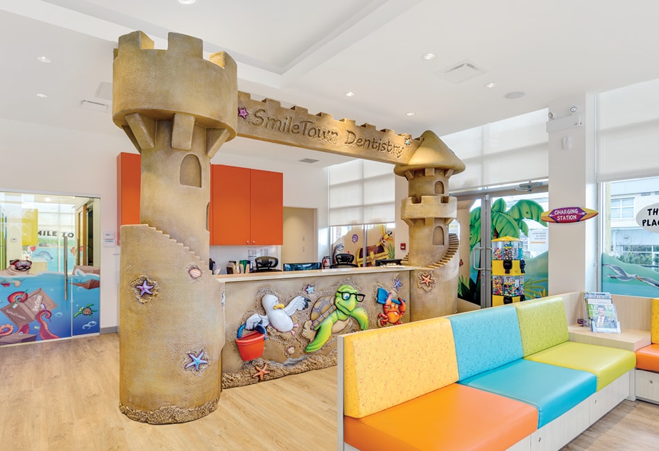 Sandcastle-themed reception area with sculpted towers and colorful seating in a pediatric dental office