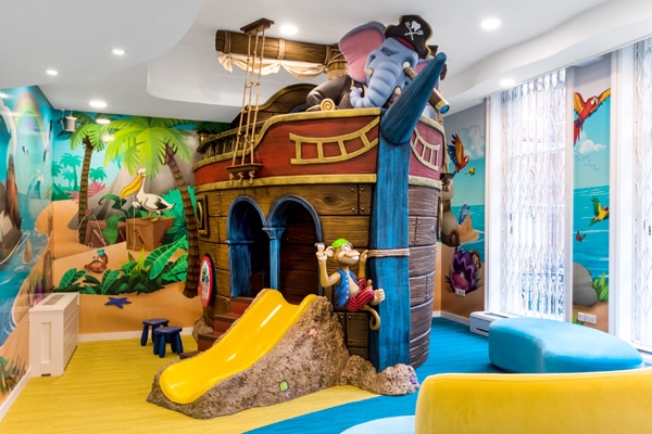 Yellow ship connected to an enclosed pirate ship play structure boarded with friendly seatmates