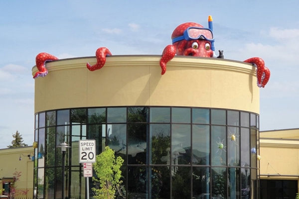 Shot of giant octopus landmark character peeking over the rooftop.
