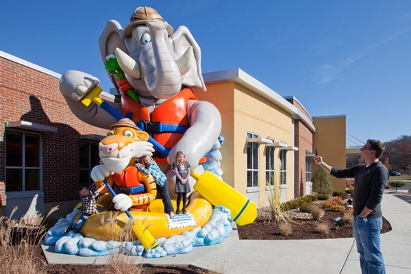 Kids posing for a photo on a giant exterior landmark of a tiger and elephant river rafting.