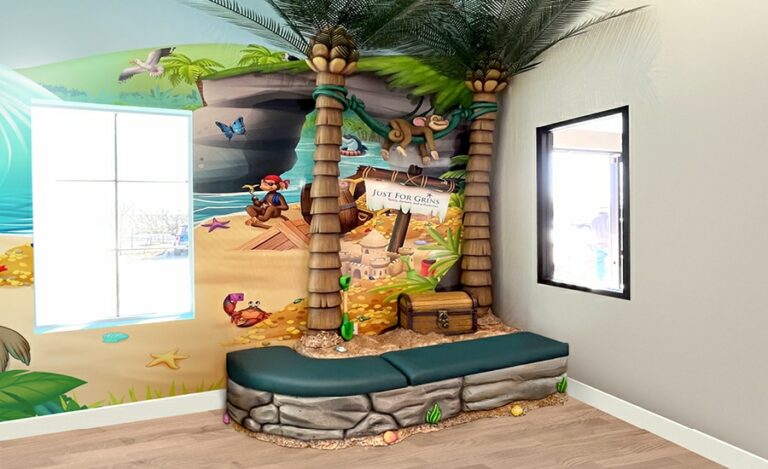 Cladded corner seating area with palm trees, a hanging monkey, and treasure chest behind.