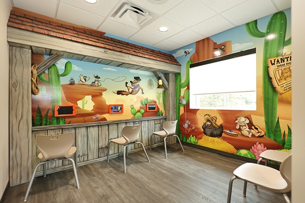 Western themed gaming area including 2d wall murals and 3D sculpted barnyard style wood posts and roof