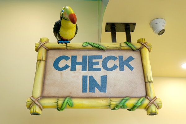 Jungle themed wayfinding 'check in' sign with a tucan on top.