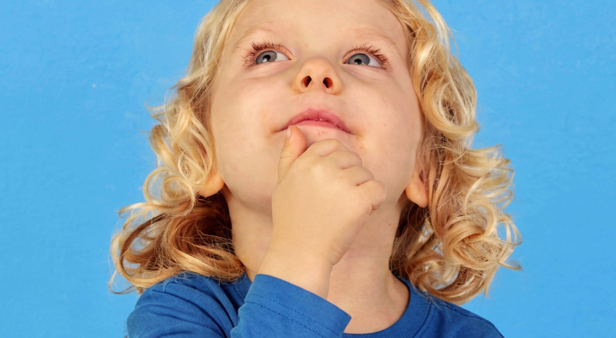 A young child with curly blonde hair and a blue shirt looks up thoughtfully, with one hand resting on their chin, against a bright blue background—an ideal image for inspiring pediatric office design.