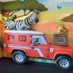 Experience a stunning themed environment transformation in this colorful safari-themed kids playroom. Before and after, the red jeep, vibrant mural animals, and playful creatures bring adventure and excitement to life.