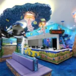 Experience a remarkable themed environment transformation in this vibrant, ocean-themed reception area. Before and after, enjoy blue floors, purple seating, colorful sea life decor, and murals of whales and underwater scenes under jellyfish lights.