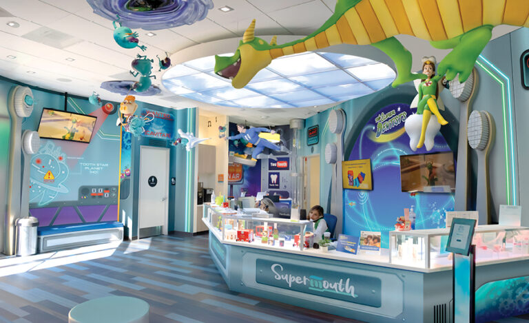 Colorful, futuristic dental office with cartoon dragon and superhero decor, bright blue floors, a large overhead dragon figure, and a receptionist at the Supermouth front desk. A playful atmosphere is enhanced by screens and displays—plus the surprising addition of a giant insect character among the decorations.
