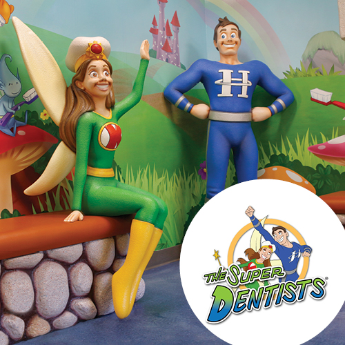 Statues of a female tooth fairy and a male superhero mascot stand in front of a cartoon wall mural, with The Super Dentists logo superimposed over the pediatric dental decor in the foreground.